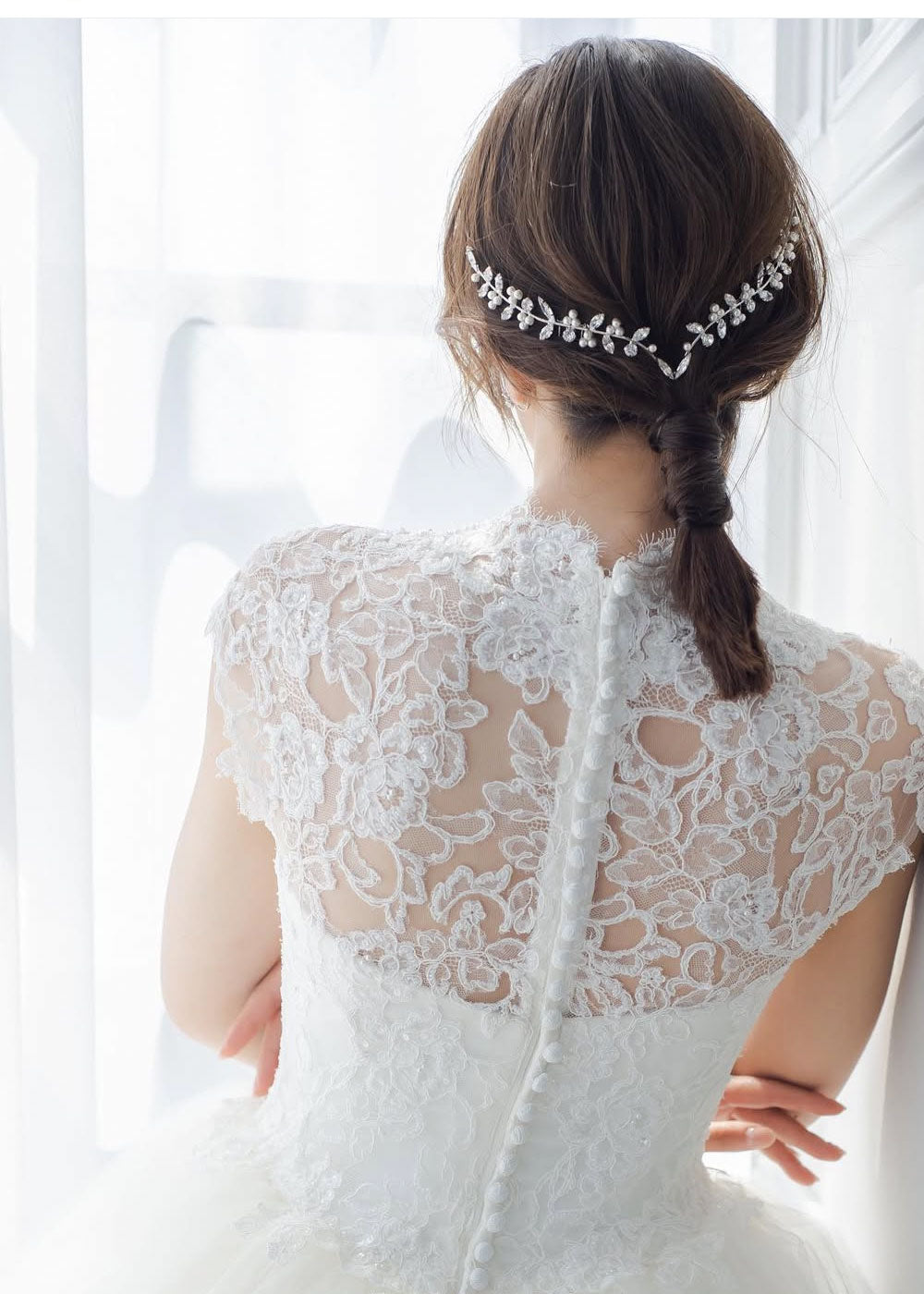 Back view of a lady wearing a crystal and pearl hairpeice and a lace wedding dress.