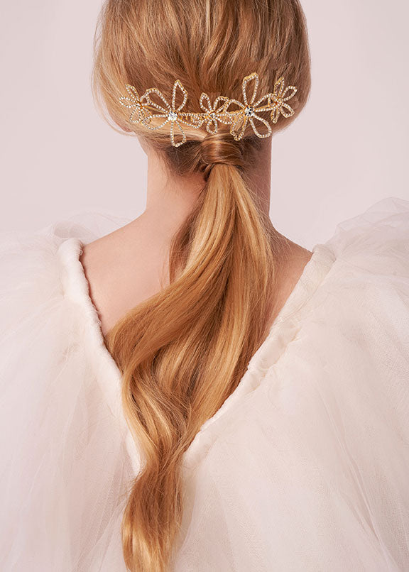 back view of a lady wearing a floral crystal hairpiece over a low ponytail