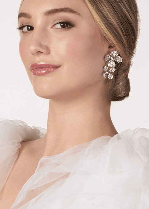 A lady wearing a floral crystal earrings against a white background