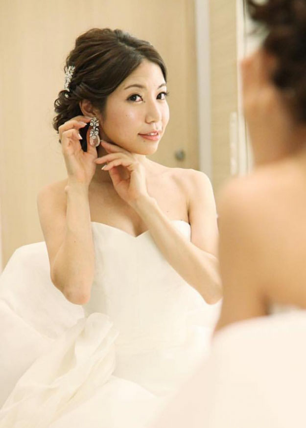 A bride looking in the mirror wearing best-selling floral tear drop earrings in her wedding dress