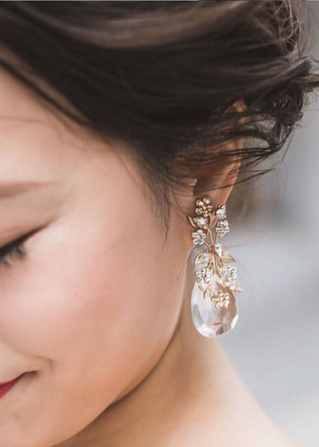 a close up of a lady wearing flora tear drop earrings.