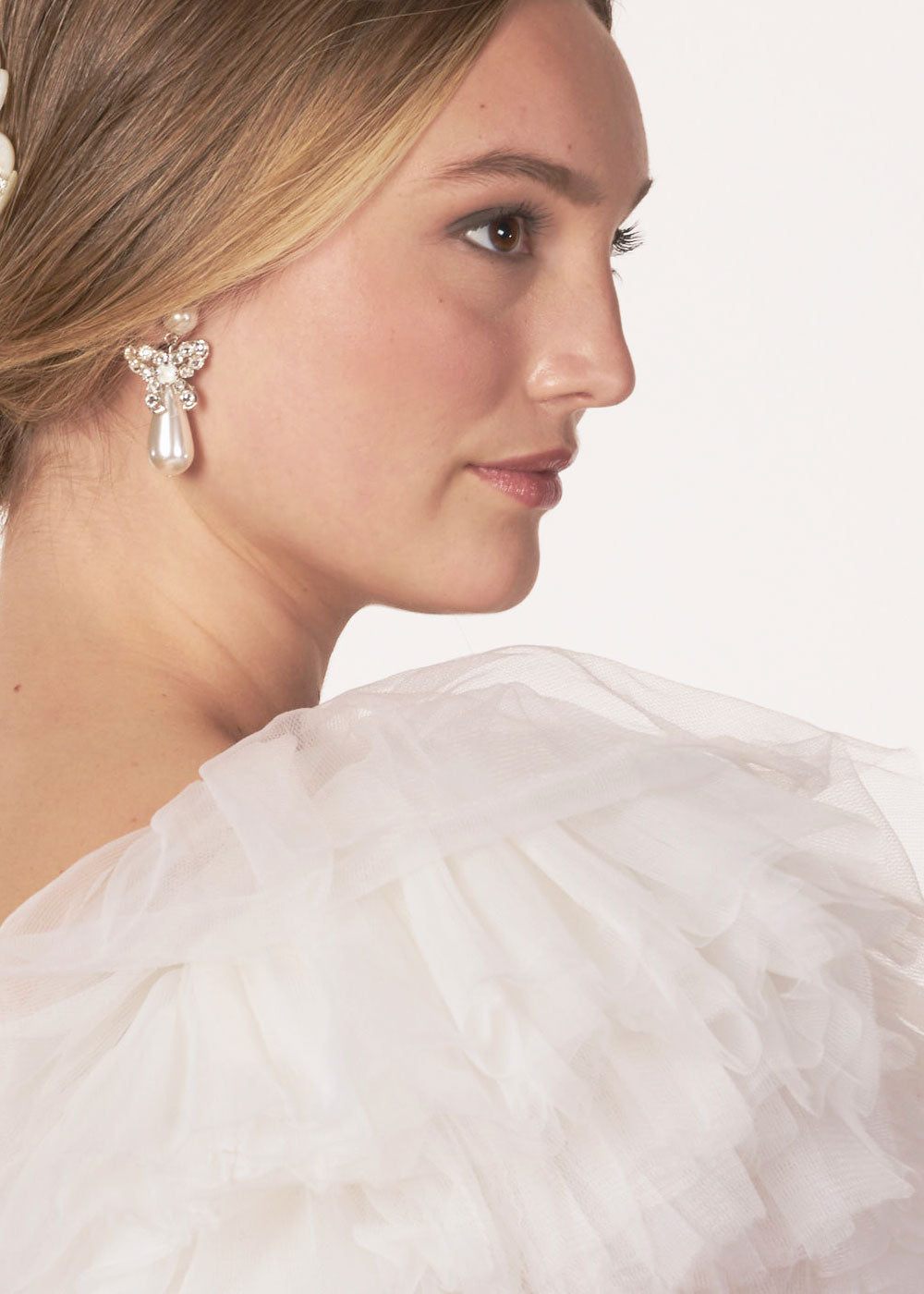 Pearl bow drop earring with crystal accents on model side view tulle dress
