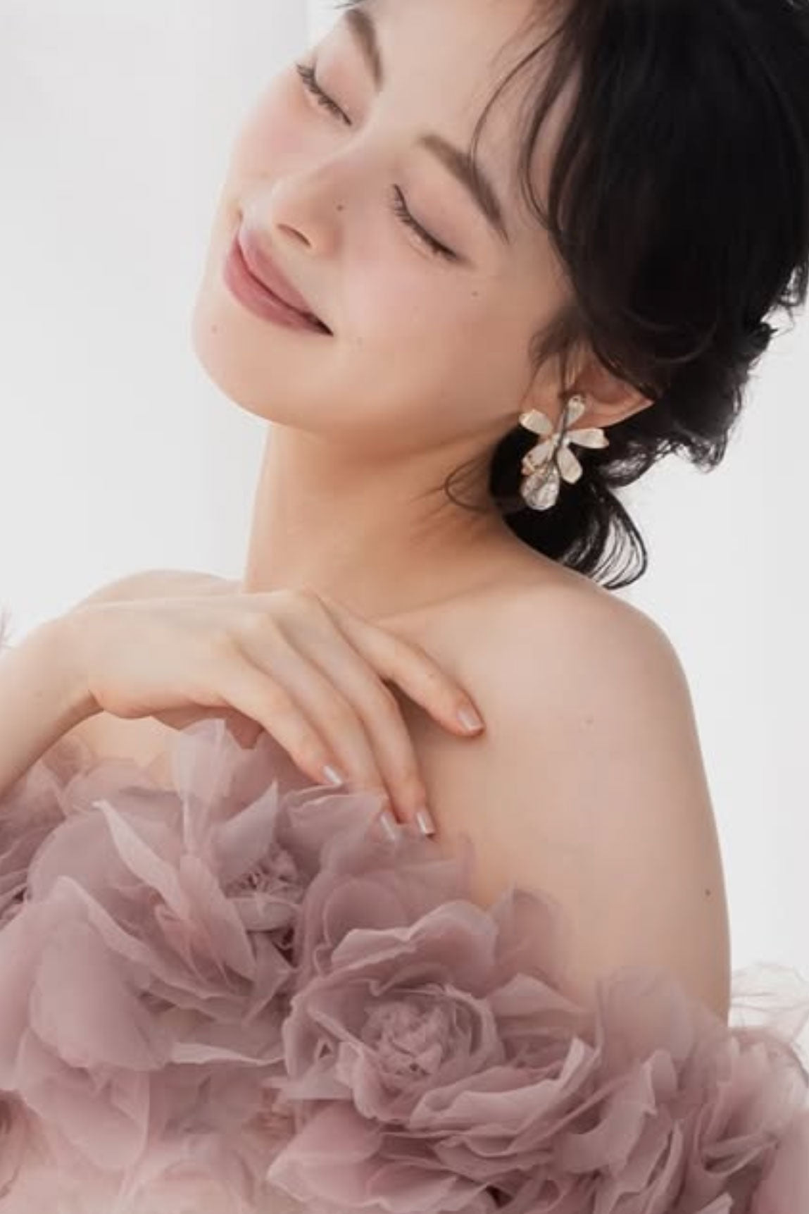 Woman wearing a floral earring with a soft pink background