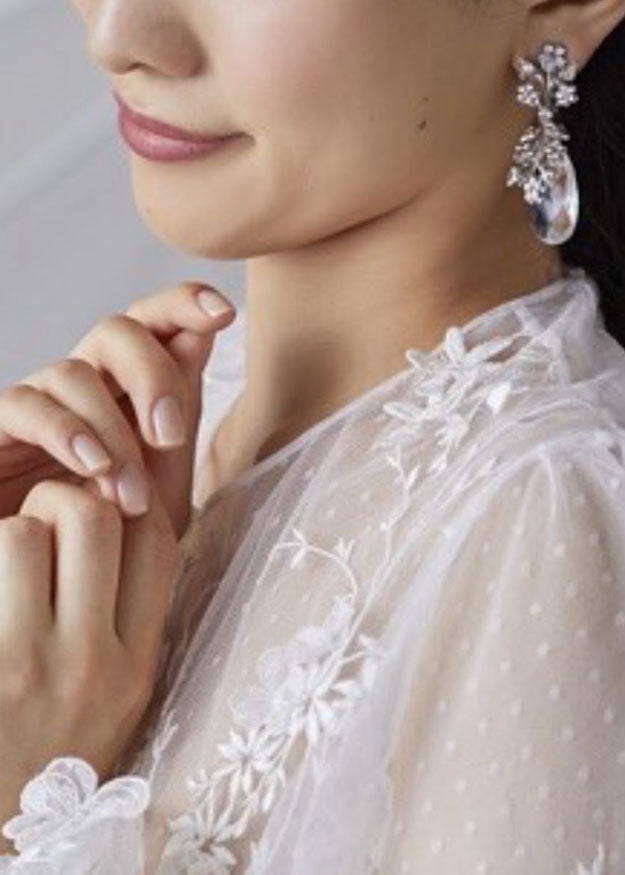 A cropped view of a lady wearing crystal teardrop earrings.
