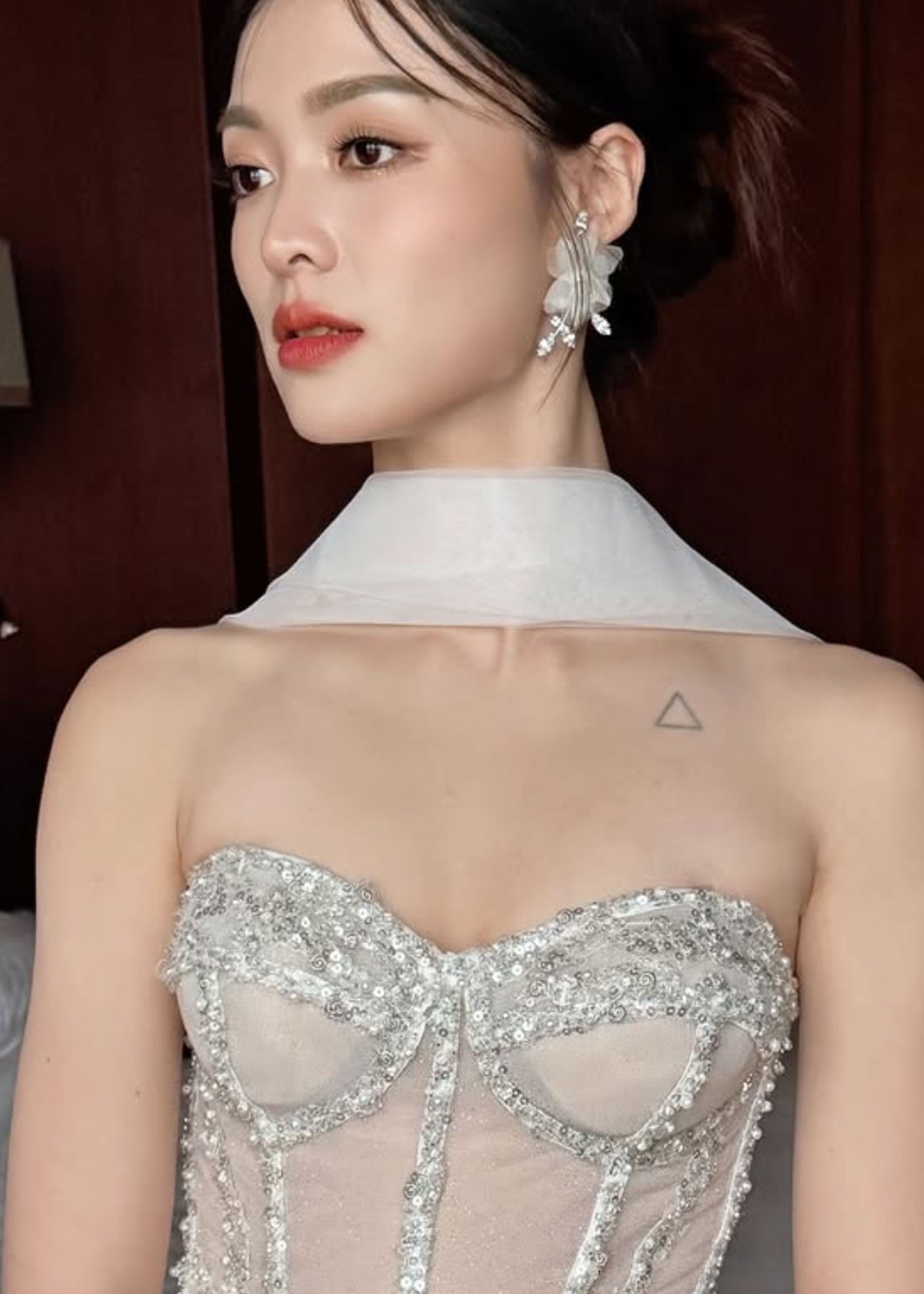 A Bride wearing a silver crystal dress,  floral stud earrings and red lipstick.