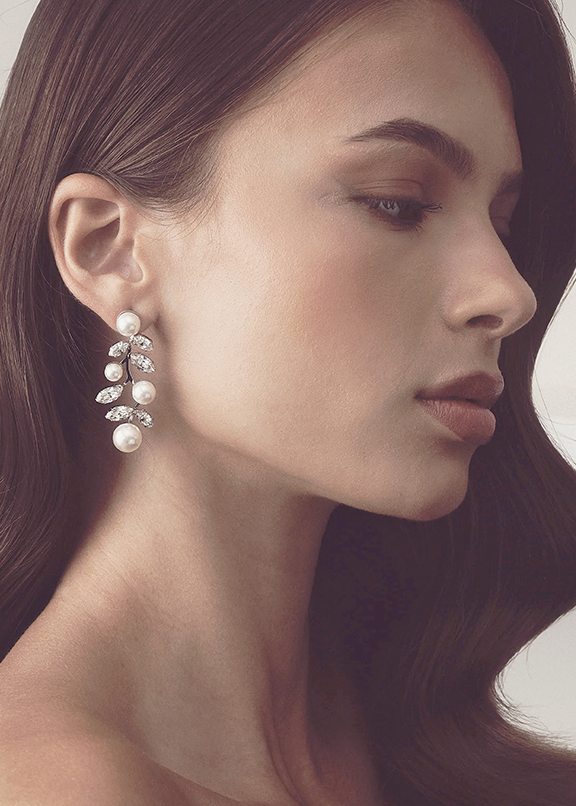 Close-up of a woman wearing pearl earrings with a soft focus background