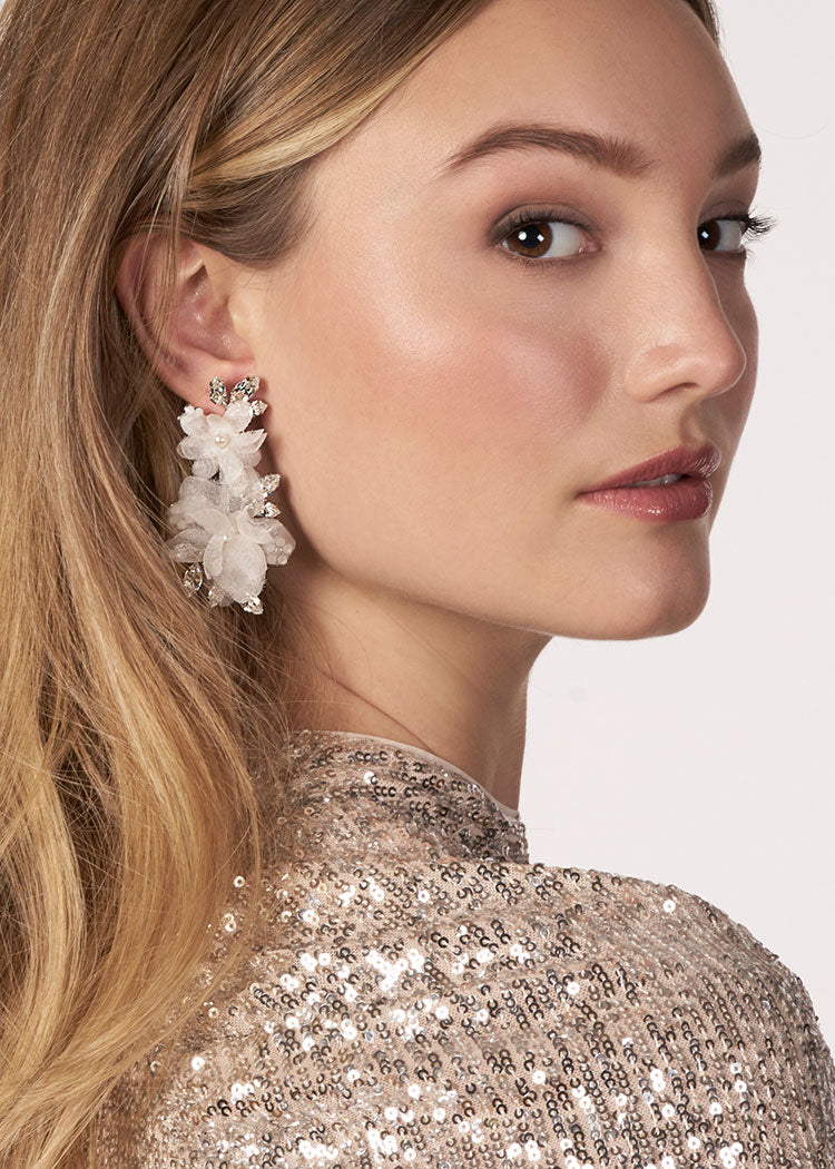 ivory floral chandelier earring made with silk flower, crystals and pearls on model in sequin dress (side view)