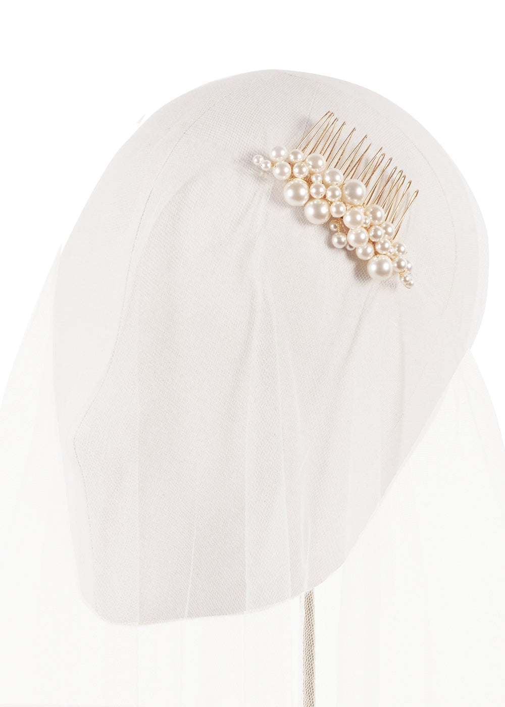 A gold clsutered pearl comb on a headstand cvered in tulle.