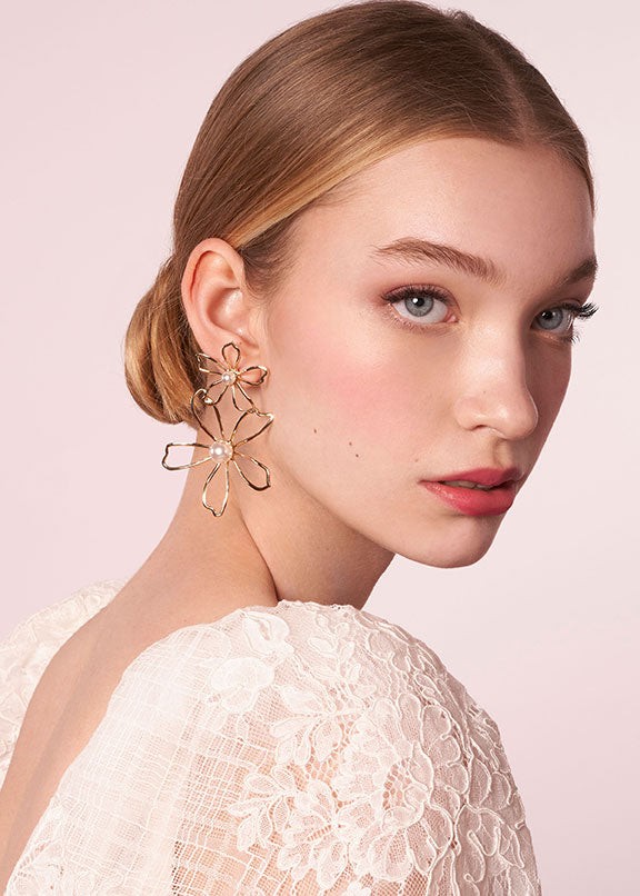 Open double flower stud earring in gold with pearl accent on model in lace dress portrait (side view)