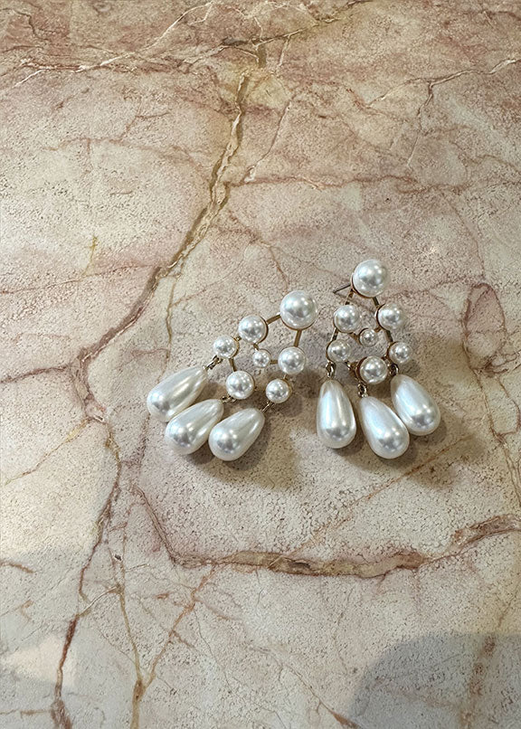 Pearl chandelier earrings laid out on a piece of blush marble