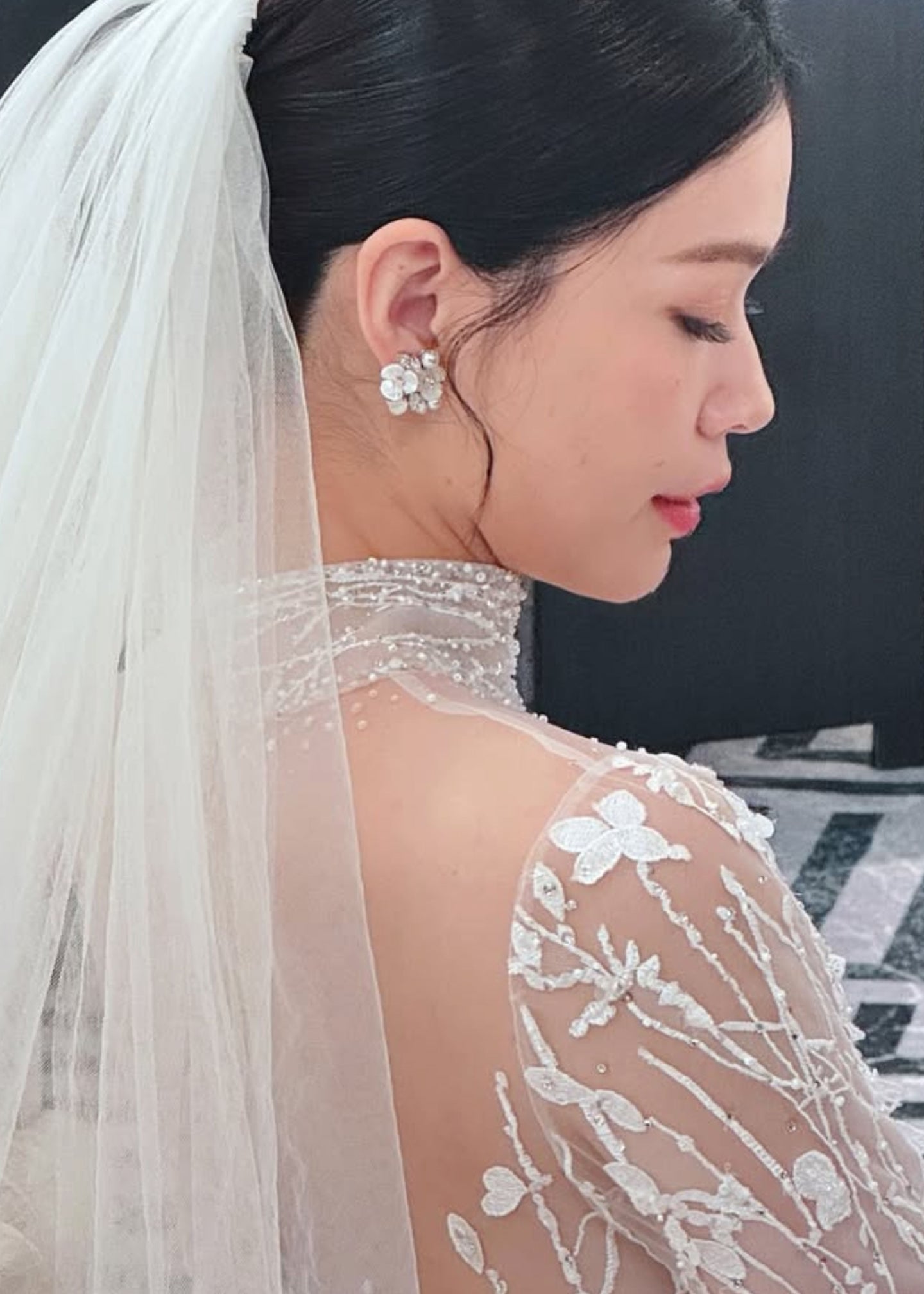 A bride wearing a cluster pearl earring and  a veil