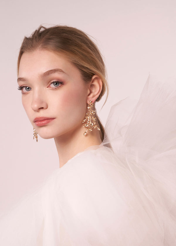 Gold floral statement earring on model in tulle dress (portrait side view)