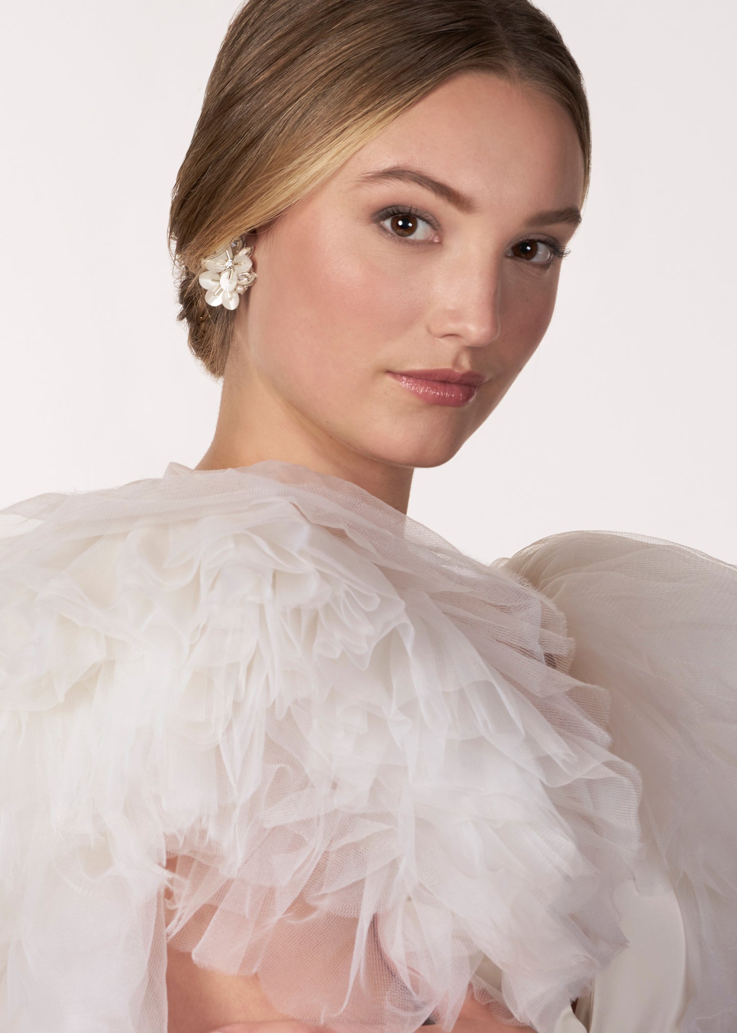 Floral clustered earring, made from sequins, pearls and crystals on a model in a tulle dress (side view)