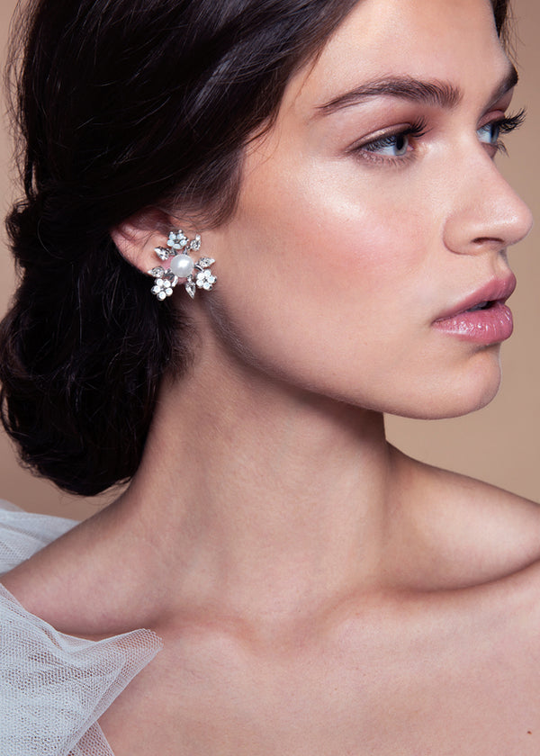A pair of pearl earrings with a floral design, featuring a gold-colored base and pearl embellishments, set with claw-set crystals.