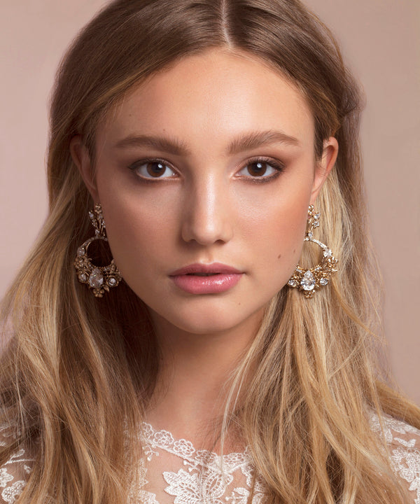 Model wearing gold floral hoops earrings