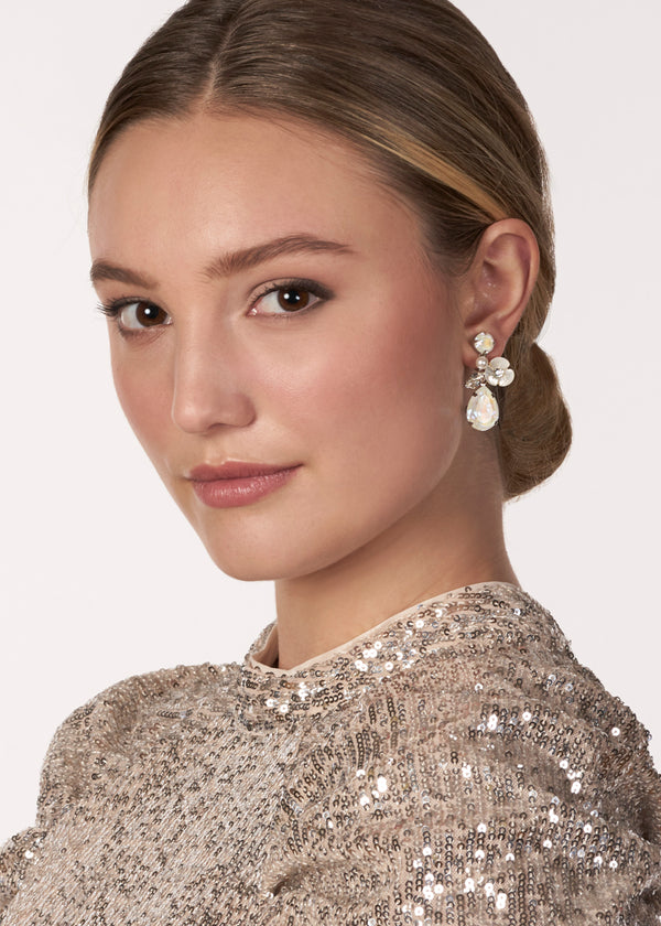A crystal and mother of pearl floral drop earring on model in sequin dress (side view)