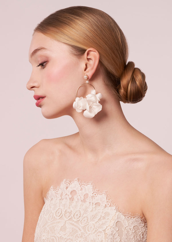 A dimensional hand sewn silk floral hoop earring on a model in a lace dress (side view)