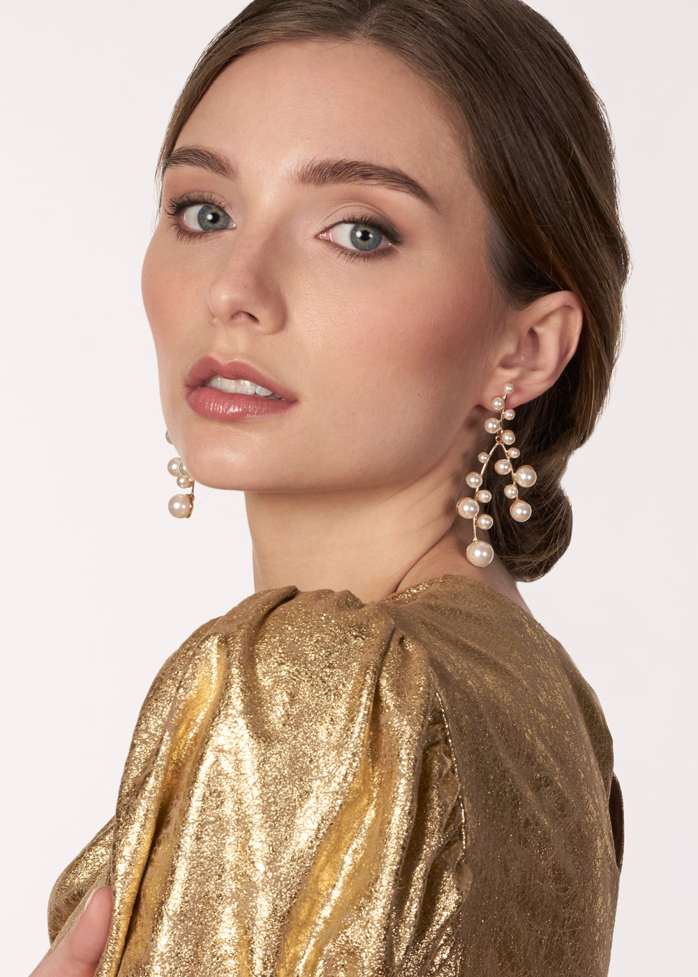 Cascading gold pearl chandelier earring on model in gold top side view