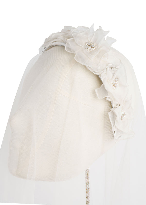A floral silk headband on a headstand with veling
