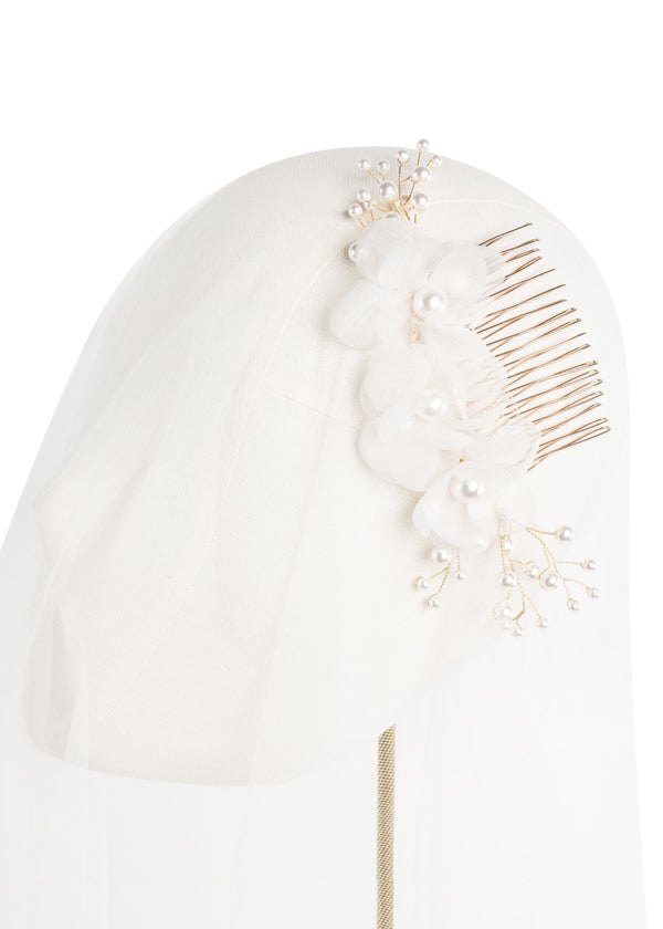 a golkd and silk floral hair comb acented with pearls postition on headstand with tulle.