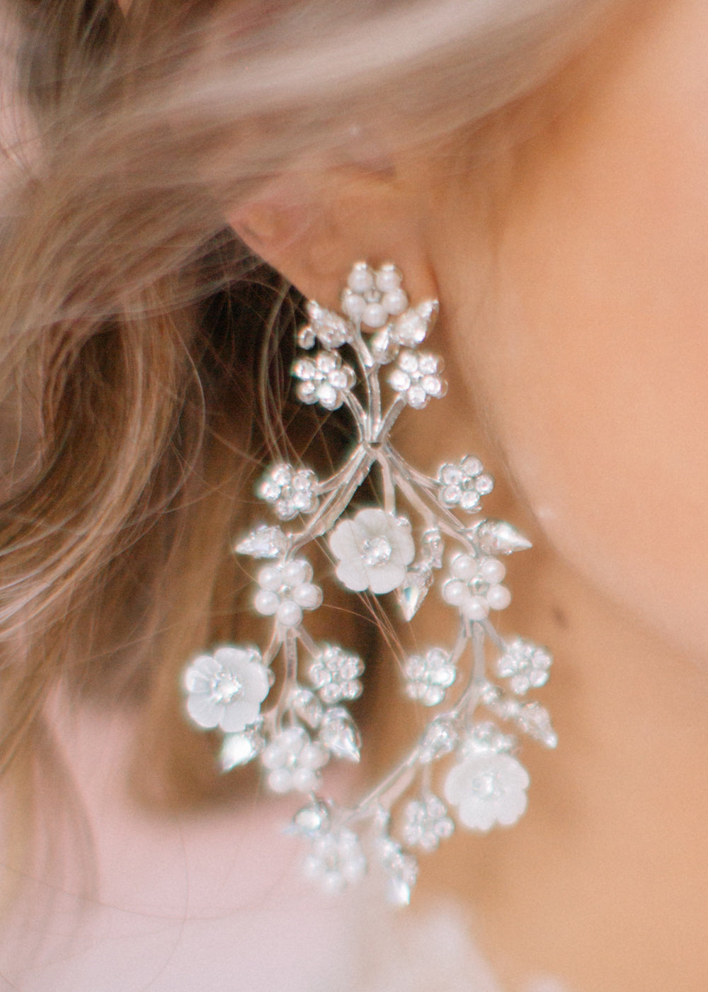 Close up of mother of pearl floral chandelier earring on model