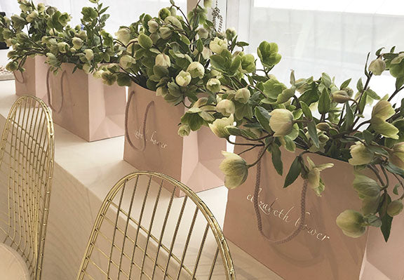 A row of pink gift bags from Elizabeth Bower filled with flowers 