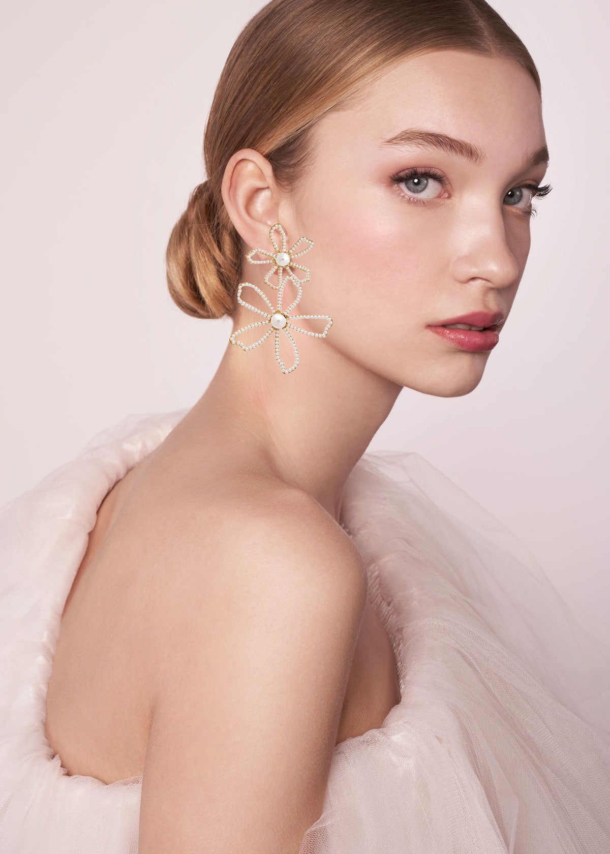 Woman wearing a floral earring against a light pink background