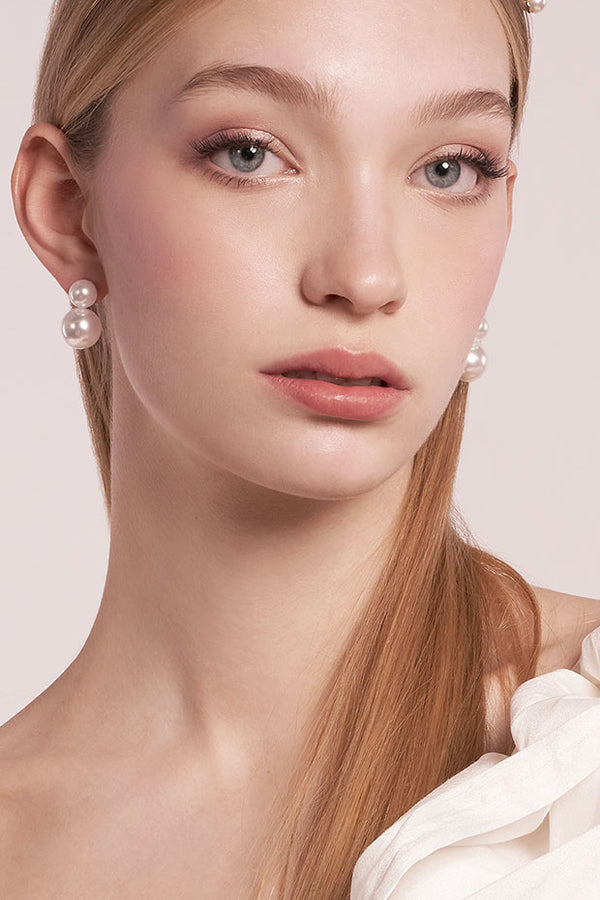 Close-up of a woman wearing pearl earrings with a soft background