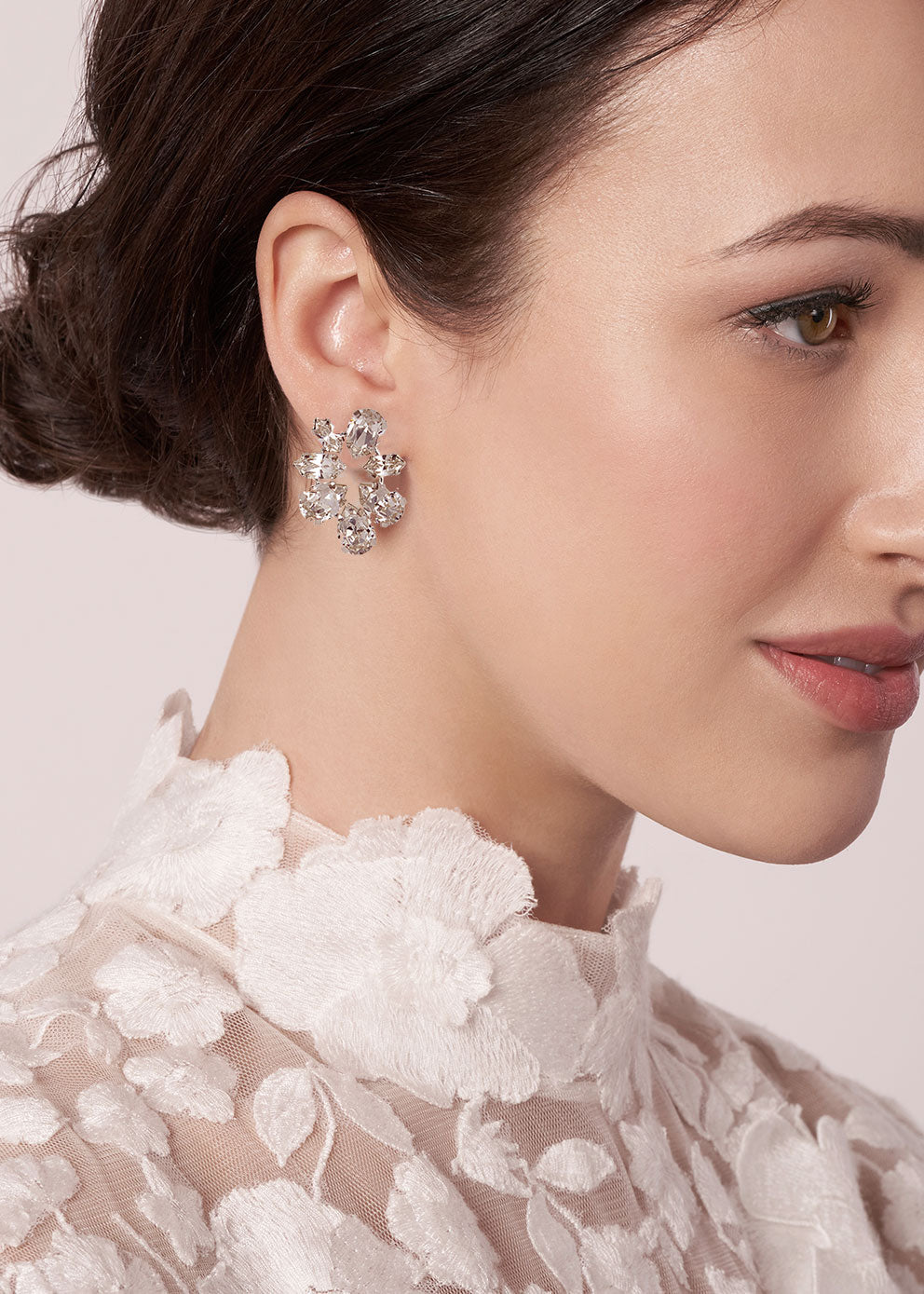 Close-up of a woman wearing a sparkling earring with a neutral background