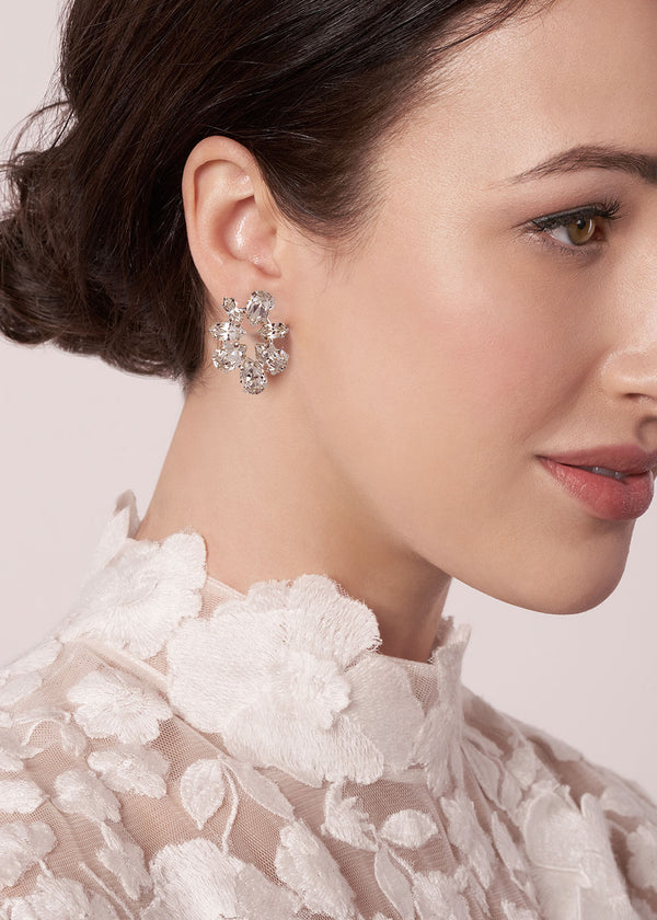 Close-up of a woman wearing a sparkling earring with a neutral background