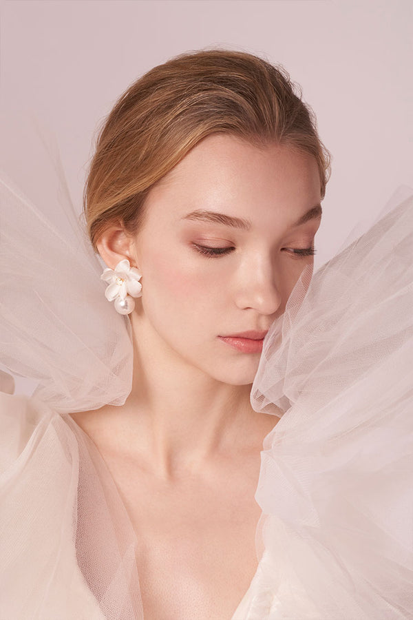 Woman wearing floral earrings with a soft, blurred background