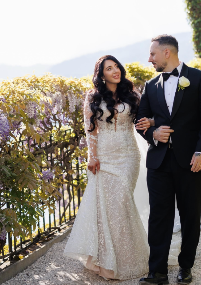 Man and woman in formal attire standing outdoors with a scenic background