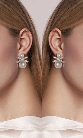 Close-up of a woman wearing pearl earrings with a plain background