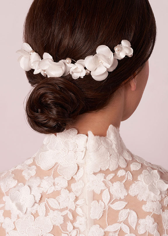 Back view of a lady wearing a silk and pearl floral hairpeice over a low bun