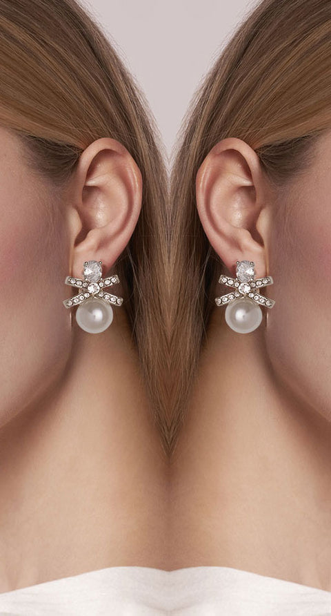 Pearl earrings with silver accents worn on a model's ears.