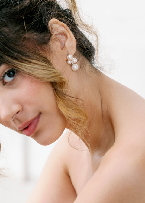 Close up of a bride wearings pearl cluster earrings and with loose curls of hair