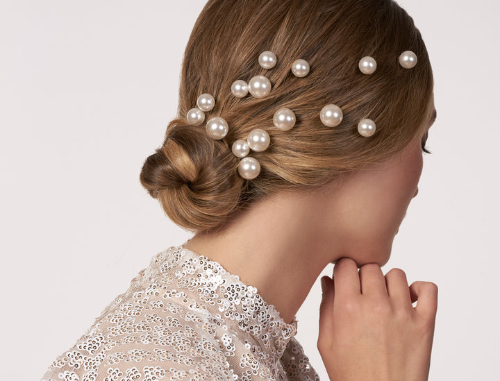 Woman with styled hair adorned with pearls on a plain background