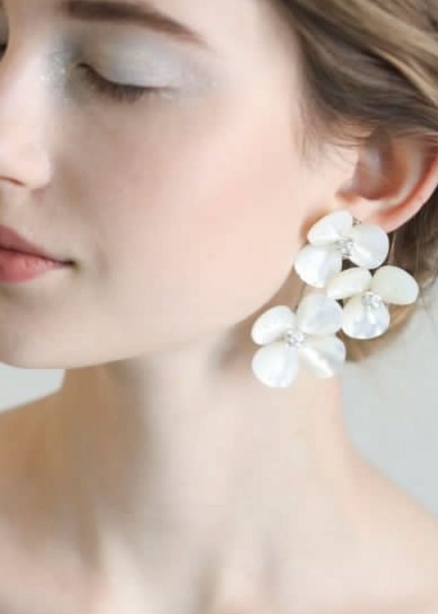 Pearl earrings worn by a model with a blurred background