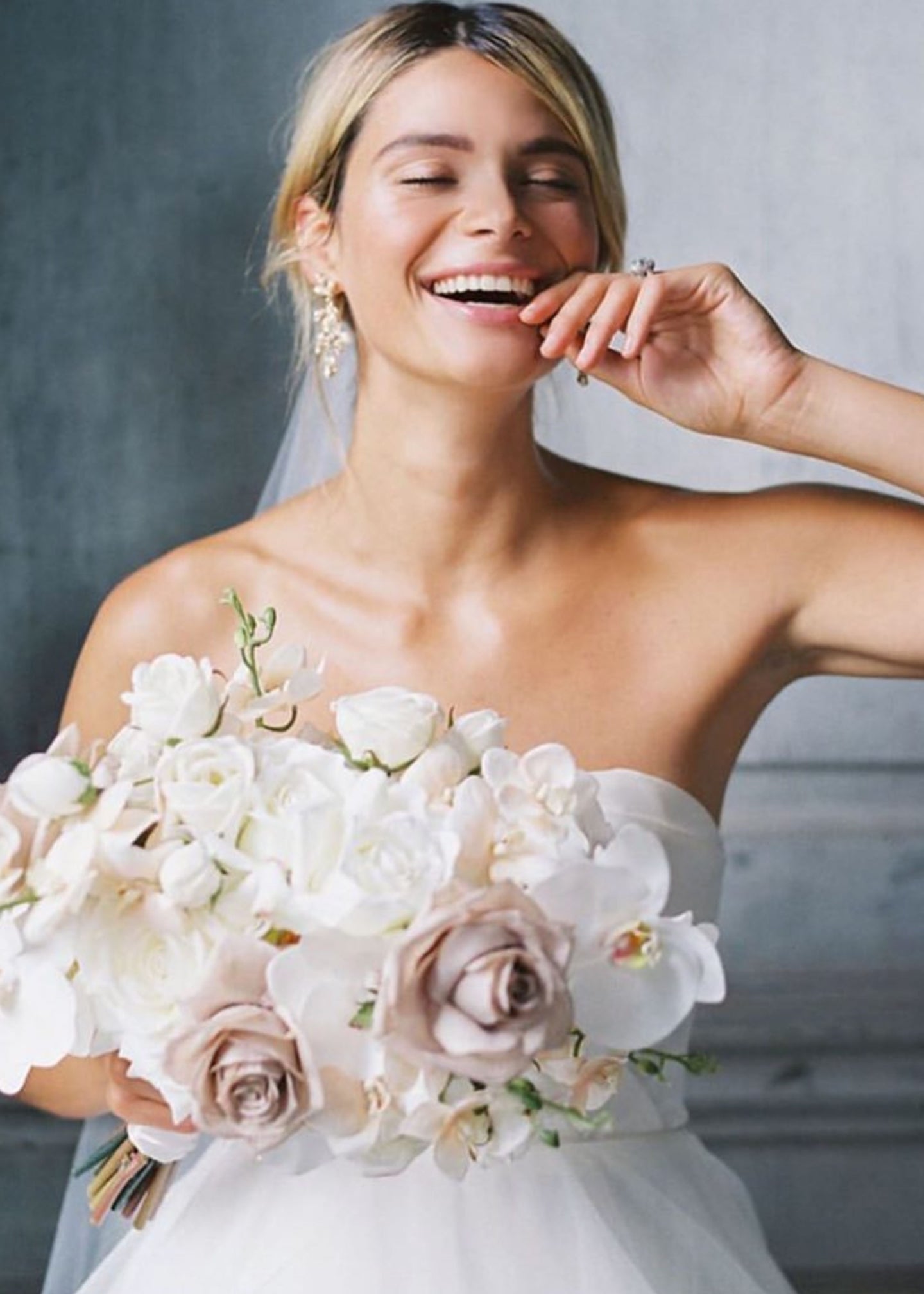 Bride holding a bouquet of flowers against a neutral background
