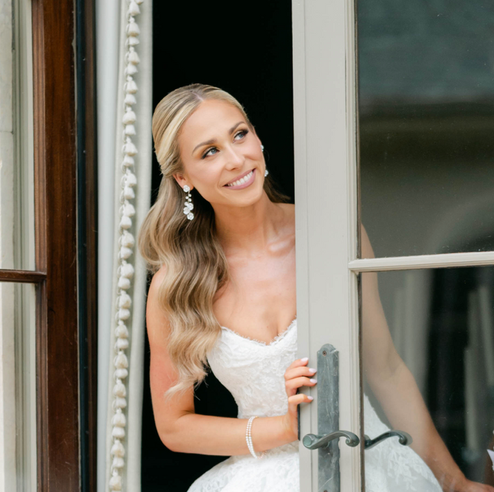 Woman in a white dress standing behind a door