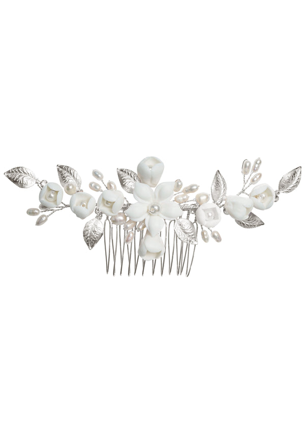 A hair comb featuring a floral design with hand wired leaves, porcelain flower, and accent crystals in a light rose gold plate finish.