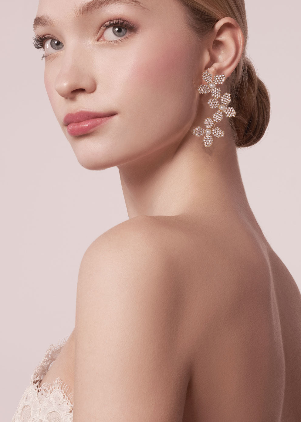 Woman wearing floral earrings against a light pink background