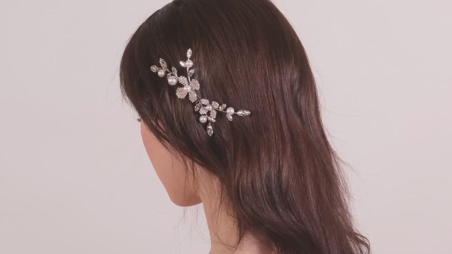 A close up image of a lady wearing a floral crystal hair comb against a blush background