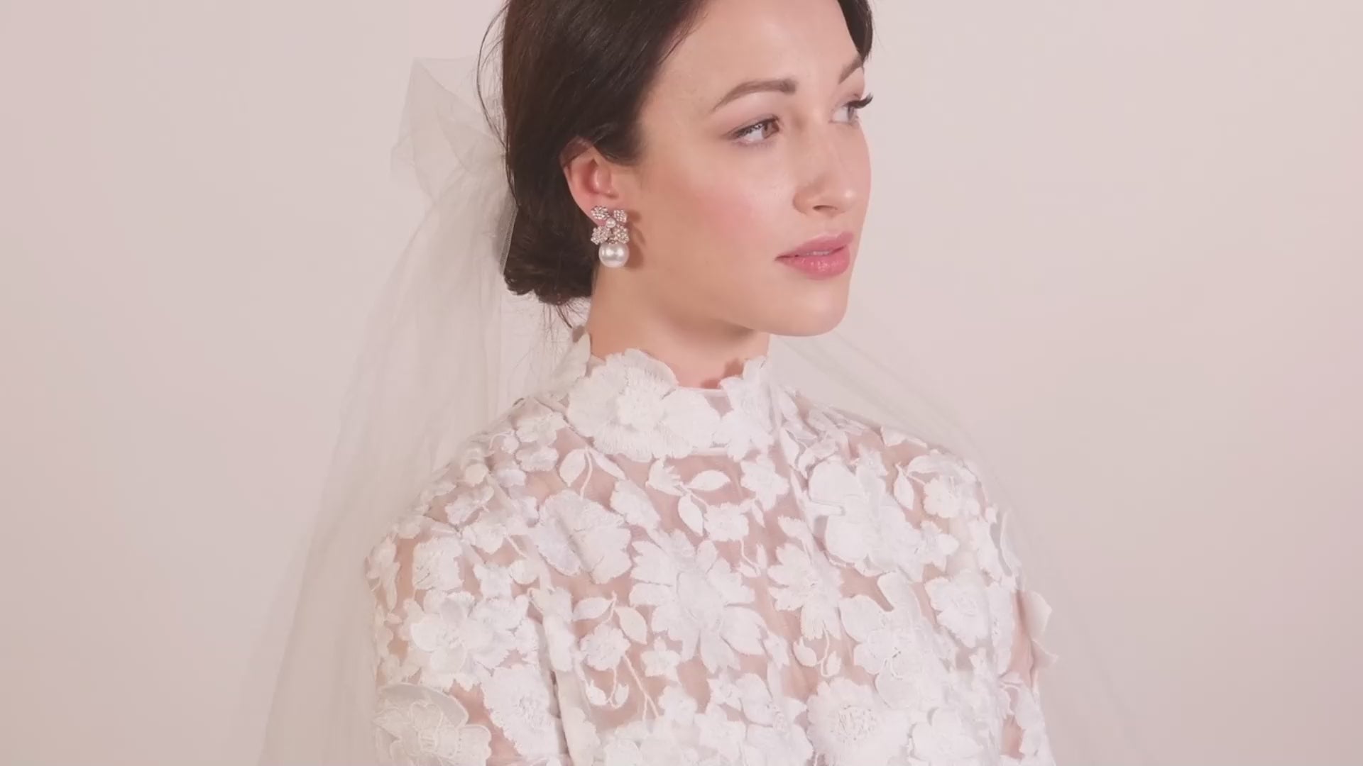 Lady wearing a lace wedding dress and a pair of crystal and pearl floral stud earrings 