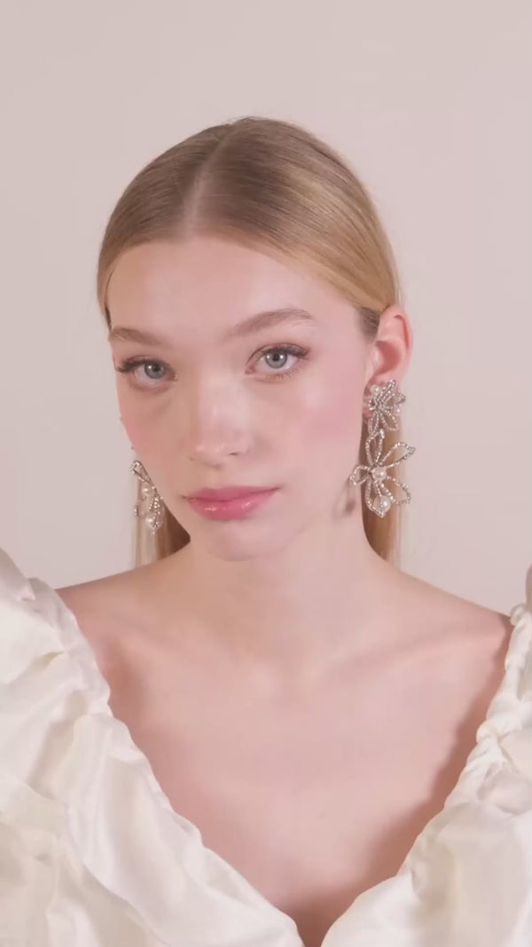 A portrait framed video of a lady with sleek hair wearing floral crystal and pearl statement earrings