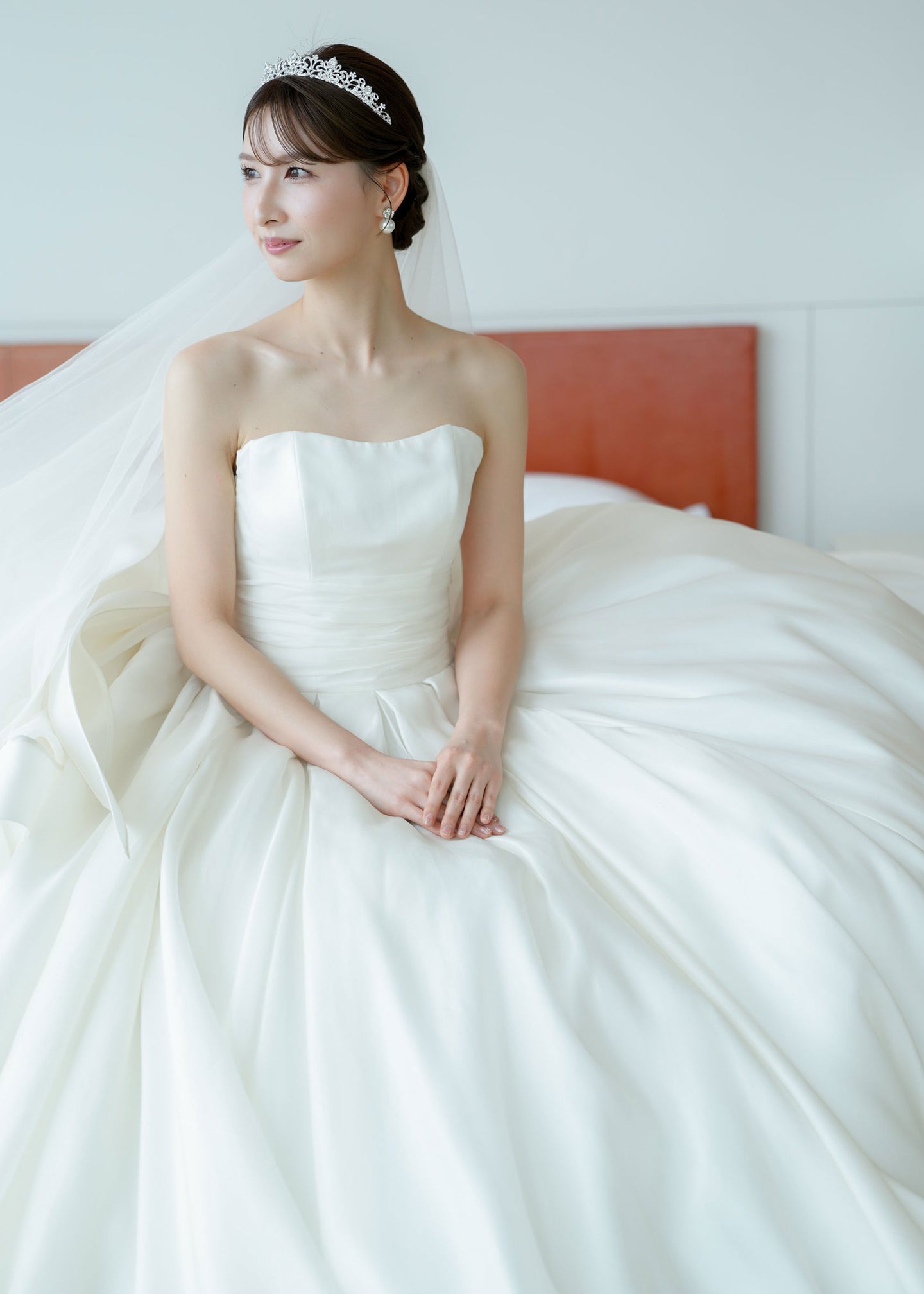 Woman in a white wedding dress with a veil standing in a room.