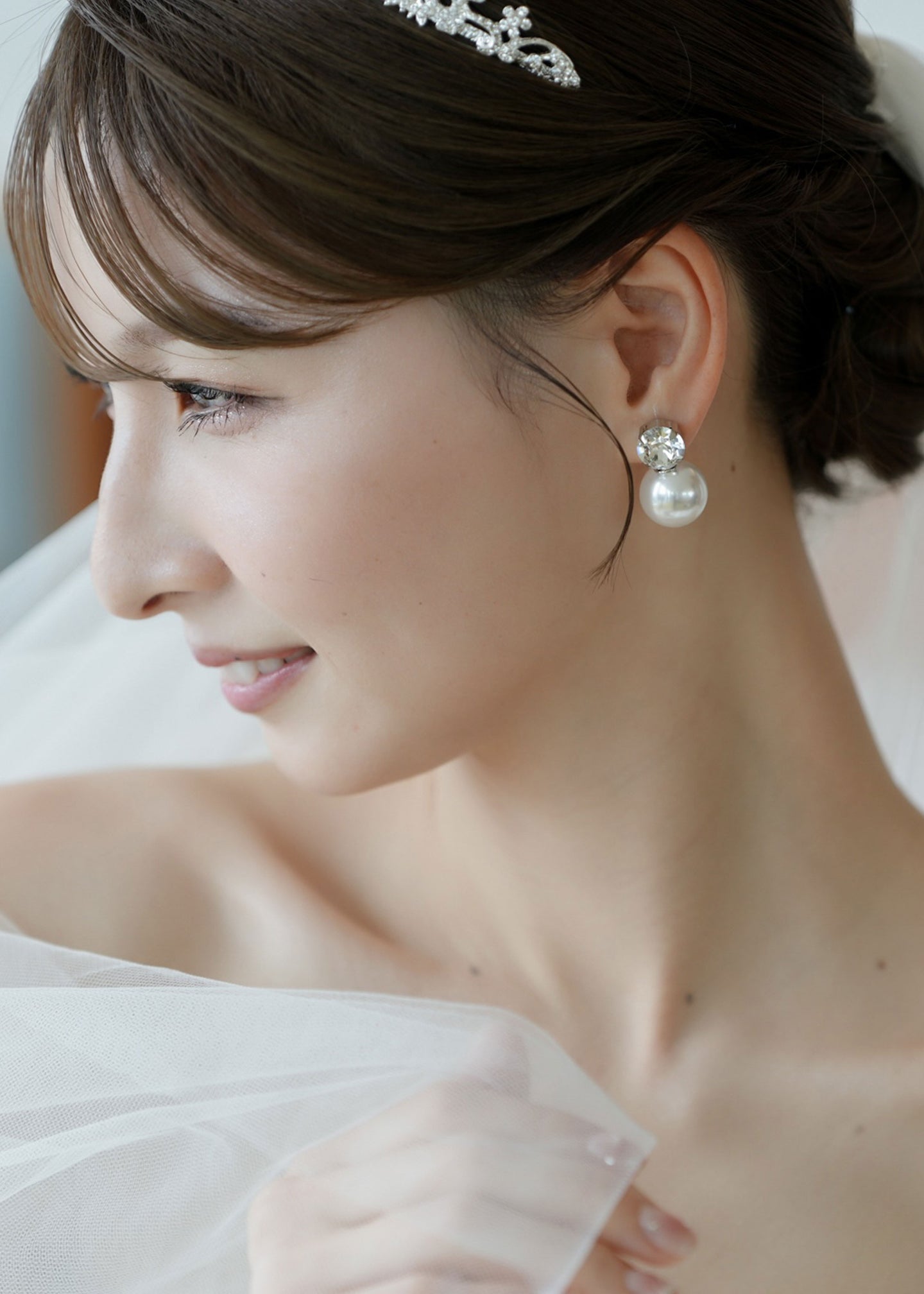 Close-up of a woman wearing pearl earrings with a blurred background