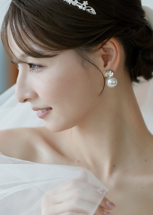 Close-up of a woman wearing pearl earrings with a blurred background