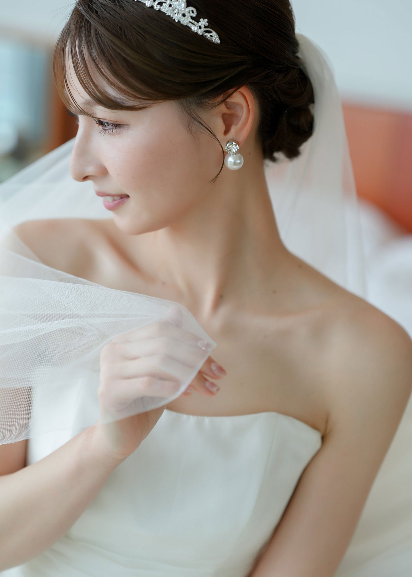 Bride wearing a white wedding dress with a veil and pearl earrings.