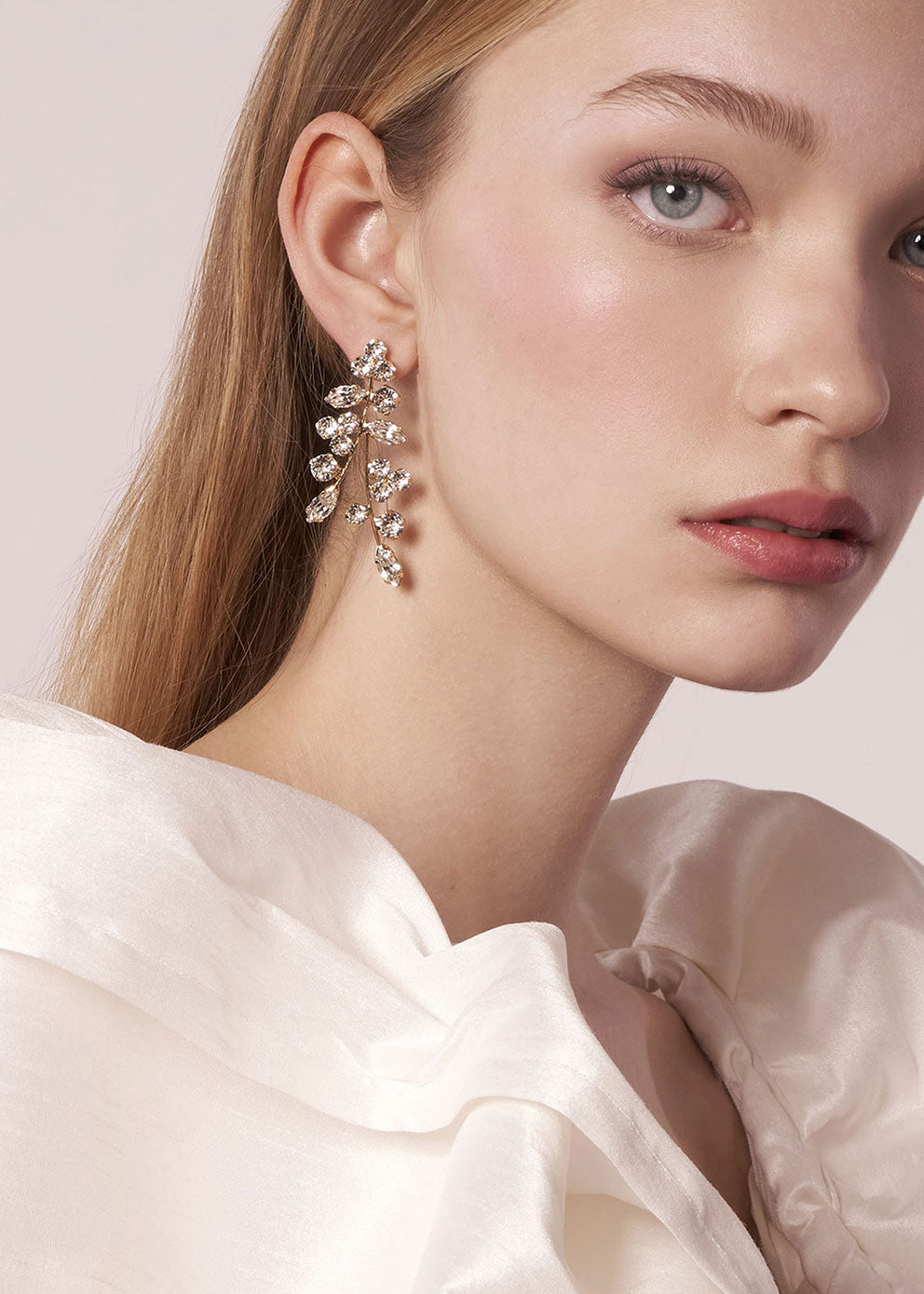 Close-up of a woman wearing a pair of diamond earrings with a soft background